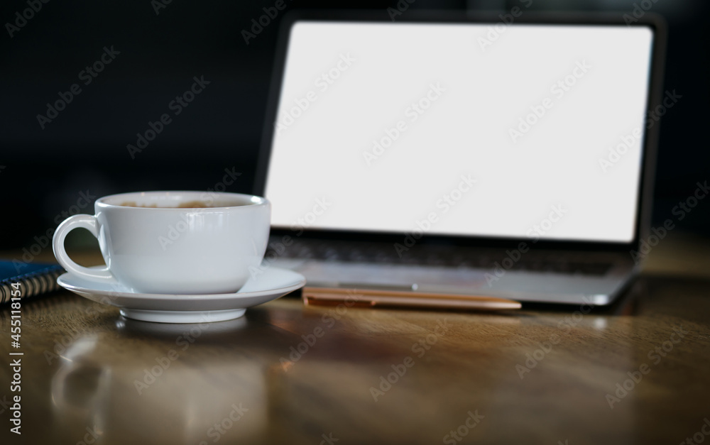 Focus on white coffe cup with computer laptop, note book on wooden table, dark tone Focus on white coffe cup with computer laptop, note book on wooden table, dark tone