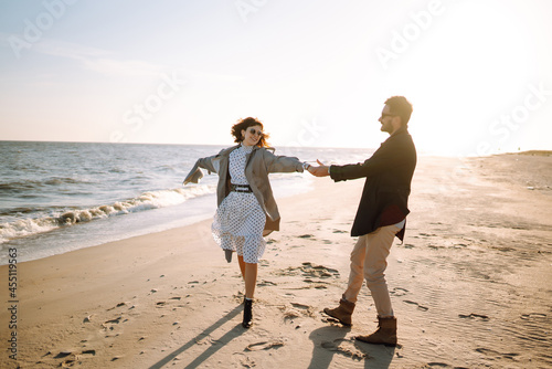 Young couple having fun walking and hugging on beach during autumn sunny day. Relaxation, youth, love,  lifestyle solitude with nature.