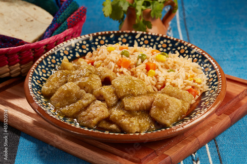 Chicharrón en salsa verde con arroz rojo mexicano servido en plato de barro
