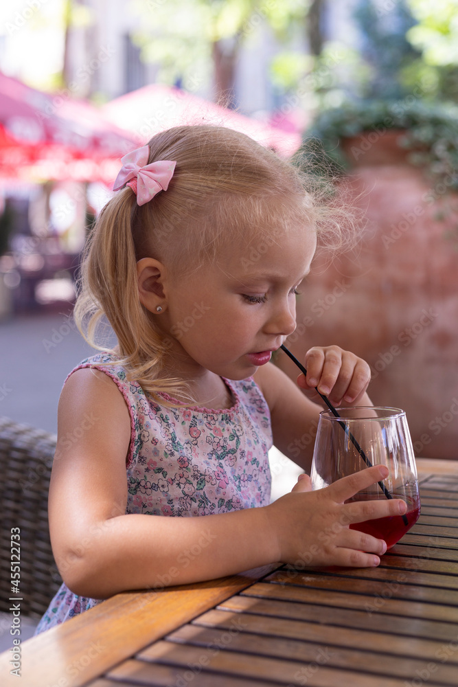 Child drinks a drink on the summer terrace under natural light. Real people Child drinks a drink on the summer terrace under natural light. Real people