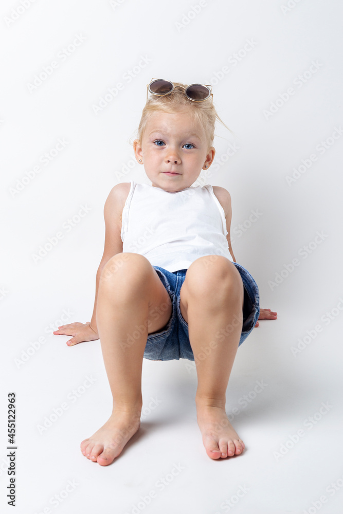 Blond child with sunglasses posing on a light background in the studio Blond child with sunglasses posing on a light background in the studio