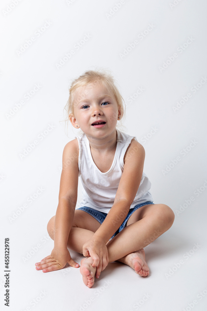 Child in a T-shirt, shorts sitting in the studio on a light background Child in a T-shirt, shorts sitting in the studio on a light background
