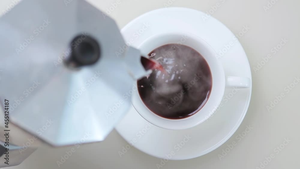 Cinemagraph, fresh brewed hot coffee pouring into white cup from geyser coffee maker, loop seamless motion, top view