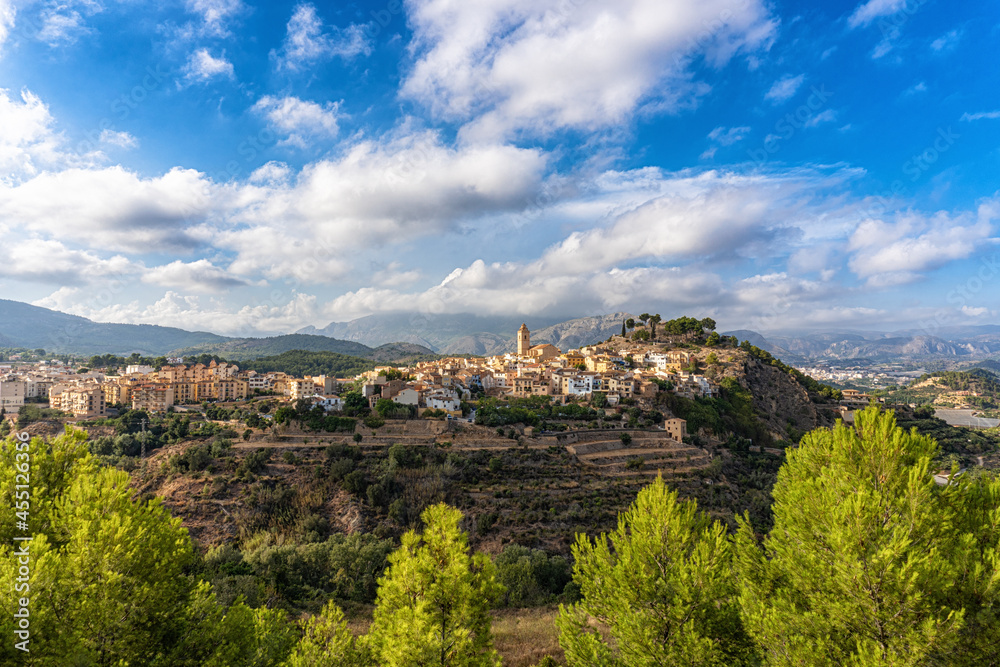 Nice landscape with the picturesque town of Polop in Alicante (Spain), with the sun's rays passing through the mountains and the clouds.
