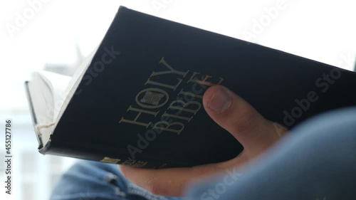 hands of young man flipping through holy bible reading holy scripture