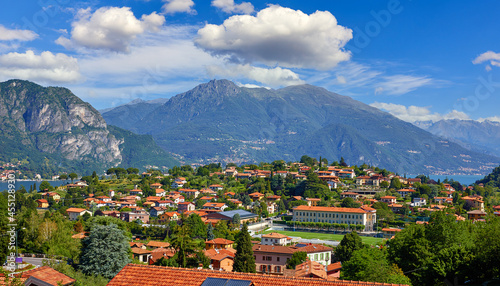 Bellagio village at lake Como, Italy. Panoramic view at hill with park and antique city among mountains and green forests. Summer picturesque landscape with water, waves and blue sky with clouds. photo