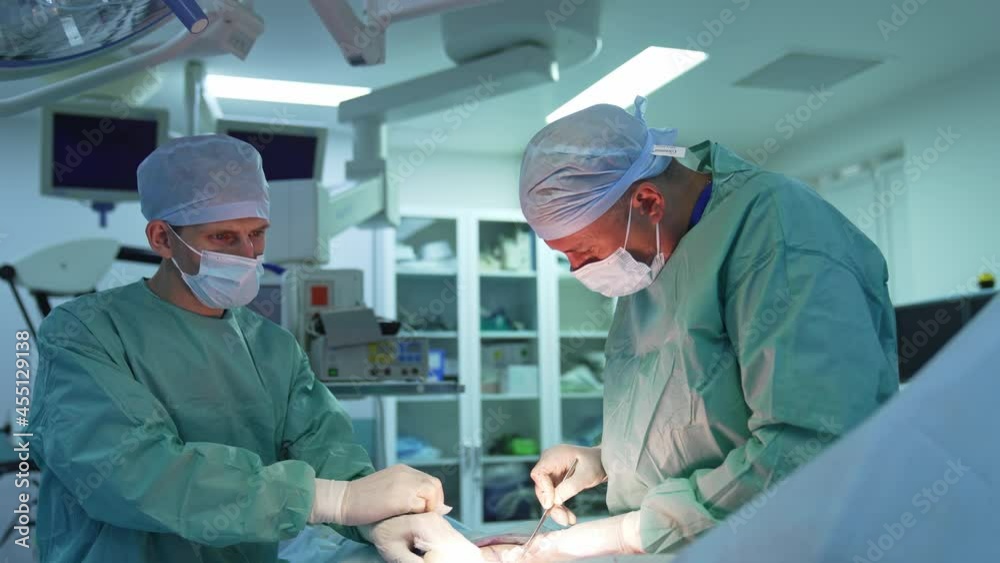 Doctor and assistant during plastic surgery. Professional surgeons perform abdominal liposuction to a patient in clinic. Surgical operation of abdominoplasty. Doctor and assistant during plastic surgery. Professional surgeons perform abdominal liposuction to a patient in clinic. Surgical operation of abdominoplasty.