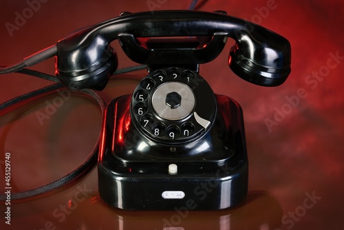 Old black telephone on red background