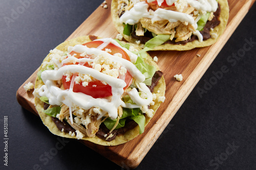 Tostadas de pollo con frijoles, crema, queso y verduras photo