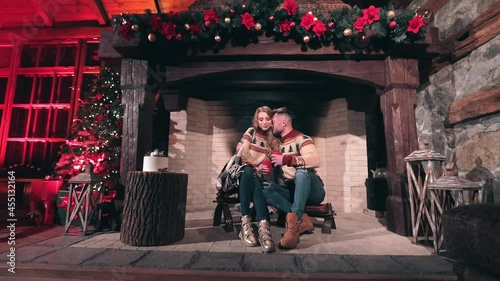 Portrait of a young couple indoors at Christmas. Man hugs beautiful woman near the firepace. Romantic atmosphere at home. photo