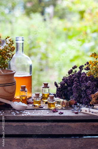 essential oil bottles with dry ingredients, wooden mortar and spoon with white crystals on the wood table in the nature