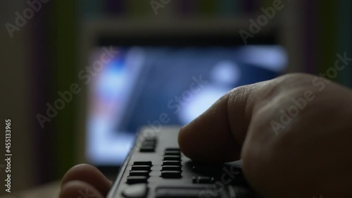 unrecognizable hand switching channels on tv set holding silver remote