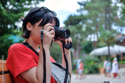 A girl looks in the viewfinder in the camera, and takes pictures at the park, selective focus