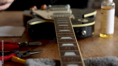 Man polishing the fretboard of black guitar