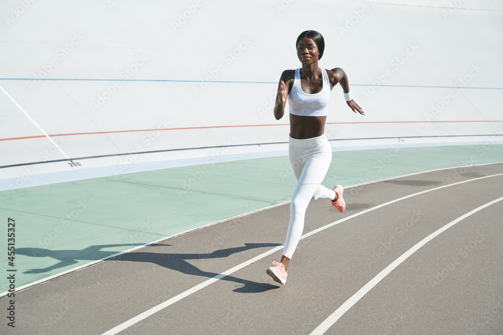 Beautiful young African woman in sports clothing running on track outdoors Beautiful young African woman in sports clothing running on track outdoors