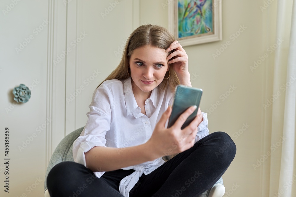 Emotional young beautiful woman looking at smartphone screen Emotional young beautiful woman looking at smartphone screen