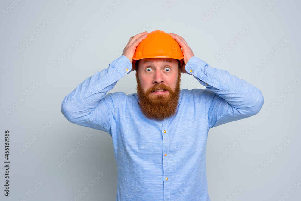 Isolated afraid architect with beard and orange helmet