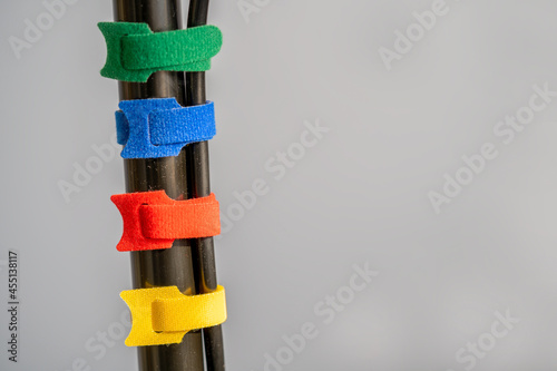 four multicolored hook and loop fabric cable ties connecting power cables together on a plain grey background