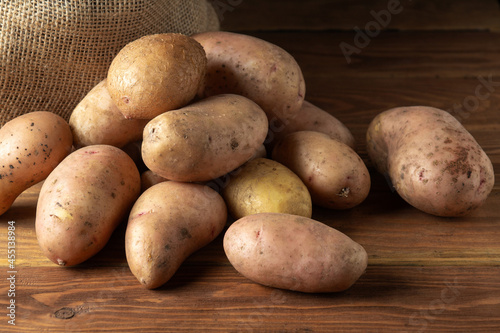 Bunch of potatoes after harvest lying on wooden boards with a potato sack in the background