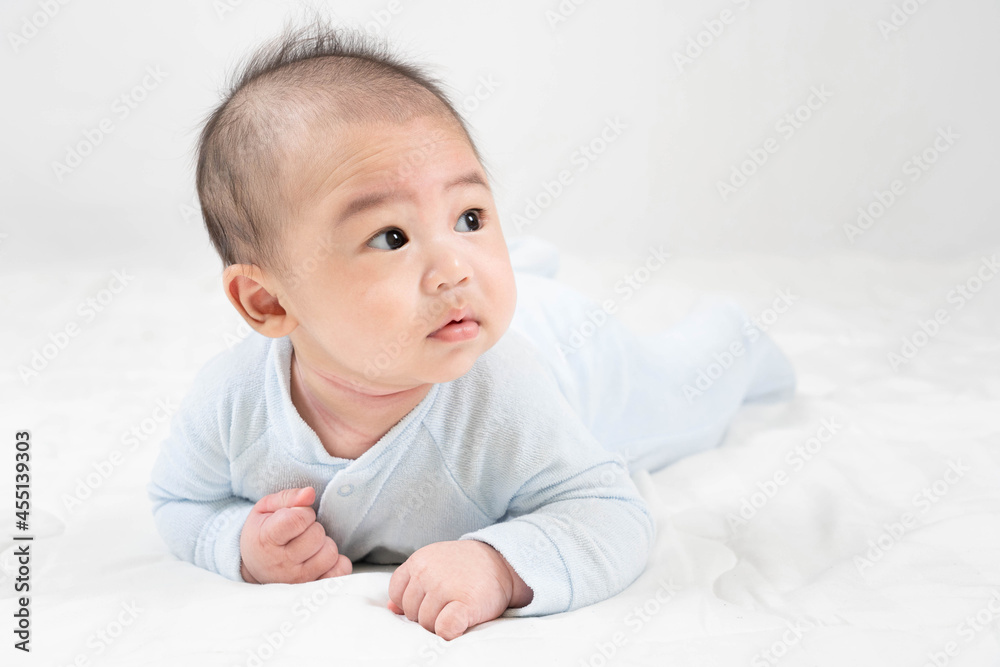 Training tummy time.Portrait of adorable young Asian newborn little baby boy prone on the bed, the child's brain will work.