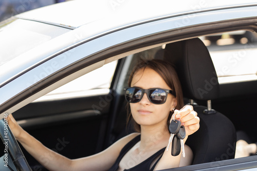 car keys in hand teenager girl, buying and renting the first car on credit,a happy woman at the wheel
