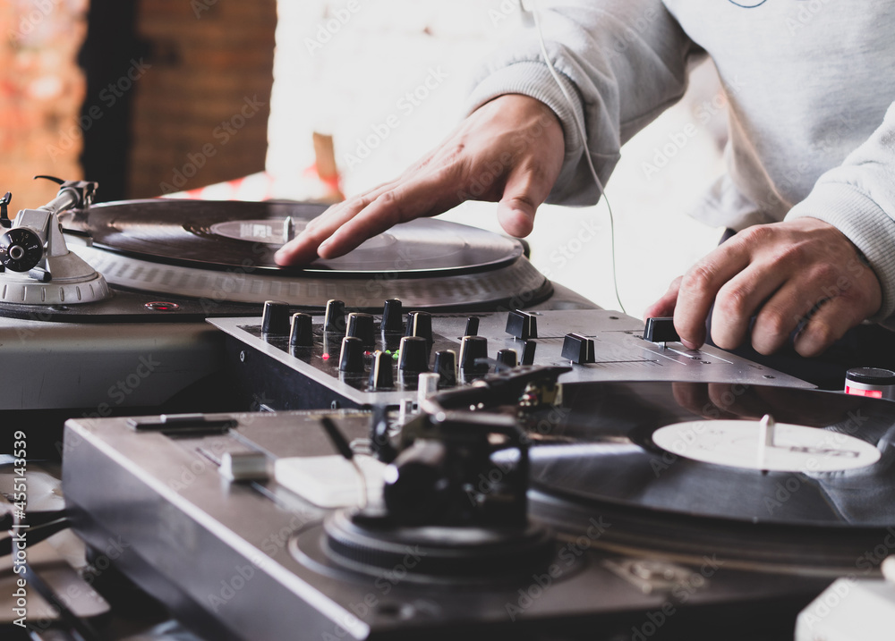 DJ playing music at a hip hop party. analog turntable, Dj uses turntable  and mixer for scratching. Photos | Adobe Stock