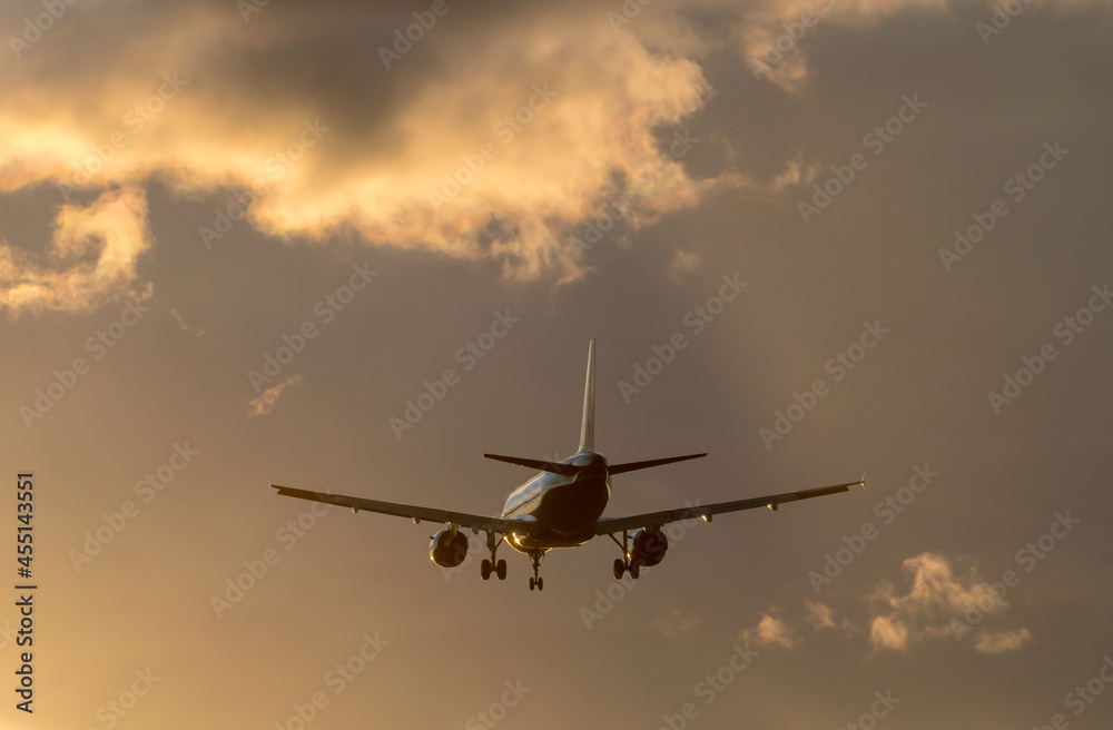 Fototapeta premium Silhouette of the airplane in the sunset colored clody sky