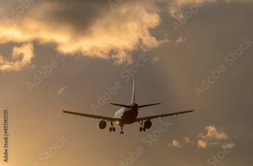Silhouette of the airplane in the sunset colored clody sky