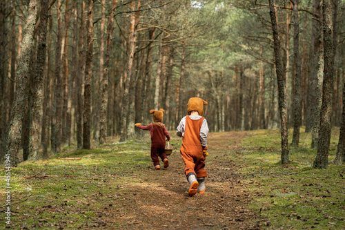 Toddler baby twins in bear bonnets playing and having fun in the woods