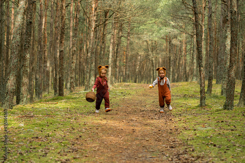 Toddler baby twins in bear bonnets playing and having fun in the woods © Sophie Garaeva