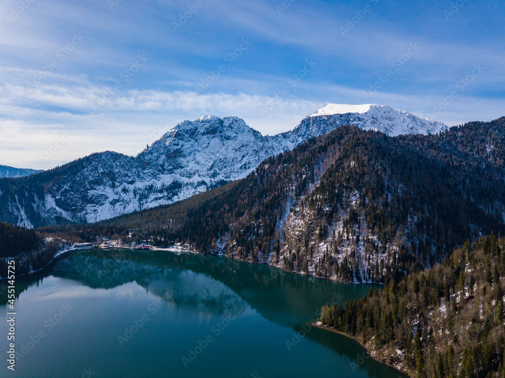 Aerial view of mountain glacial lake Ritsa in Abkhazia at winter season. Rocky mountain peaks covered with snow. Beautiful mountain landscape from drone. Abkhazia. Aerial view of mountain glacial lake Ritsa in Abkhazia at winter season. Rocky mountain peaks covered with snow. Beautiful mountain landscape from drone. Abkhazia.