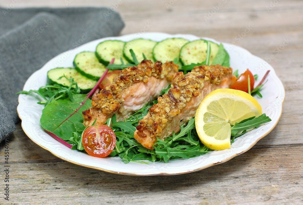 Roasted salmon fillet with walnut crust and vegetable salad - beetroot leaves, arugula, crochet, tomato, lemon