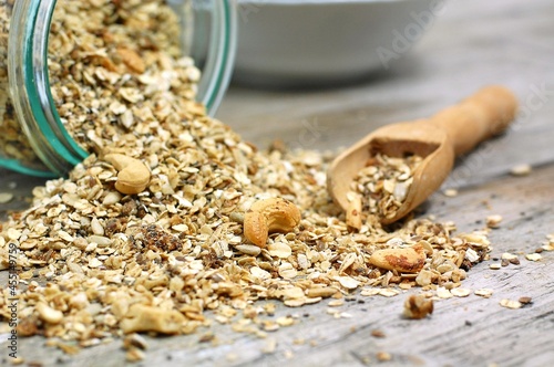 Homemade granola in white bowl with cashew nuts and seeds on grey background