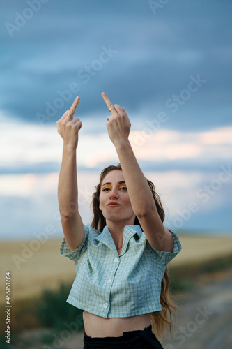 Rude woman showing fuck gesture on countryside roadway photo