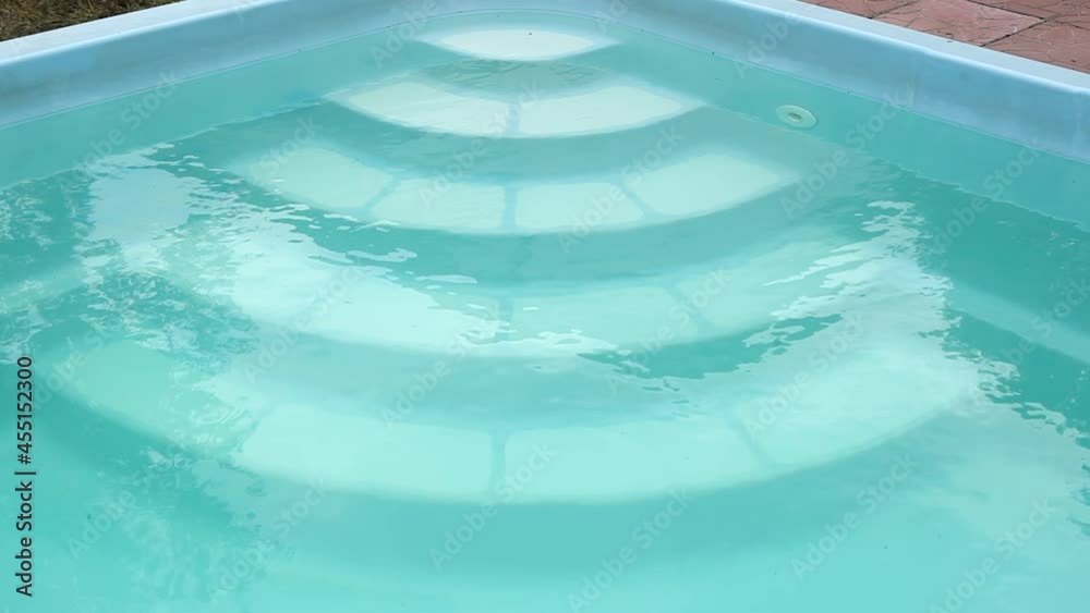 Close-up view of the steps of a swimming pool filled with water. Country pool for relaxation and rest. Blue rippling water in swimming pool. Light reflection water surface on swimming pool. Close-up view of the steps of a swimming pool filled with water. Country pool for relaxation and rest. Blue rippling water in swimming pool. Light reflection water surface on swimming pool.