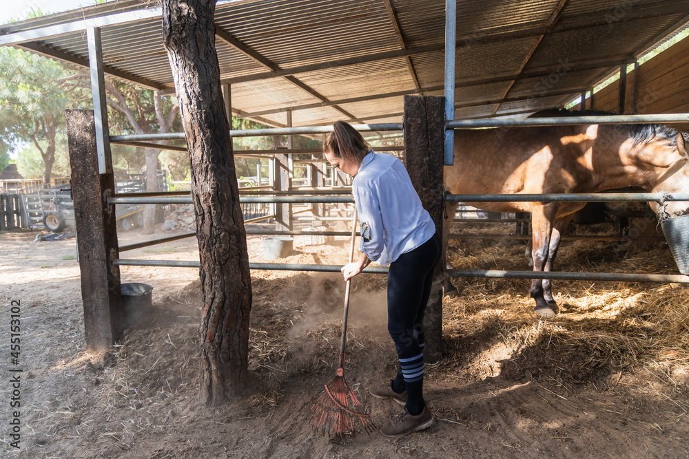 Woman carrying hay with pitchfork in stable Woman carrying hay with pitchfork in stable