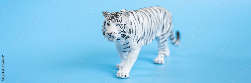 Naklejka premium the tiger, symbol of 2022 year. plastic white toy figure tiger on a blue background. banner