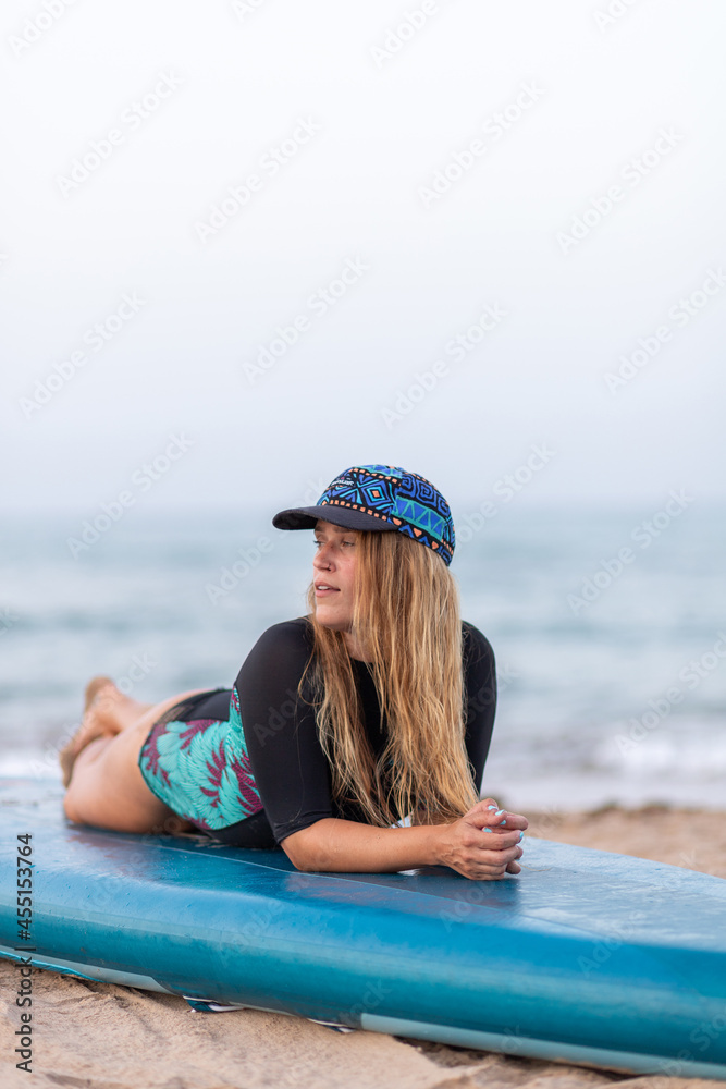 Pensive woman sitting on SUP board on beach Pensive woman sitting on SUP board on beach