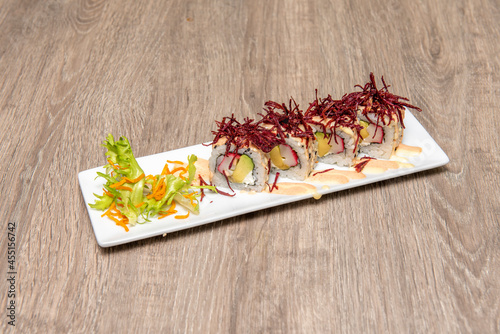 Sushi uramaki roll with avocado and surimi, nori seaweed, sauces and tengusa red seaweed on top photo