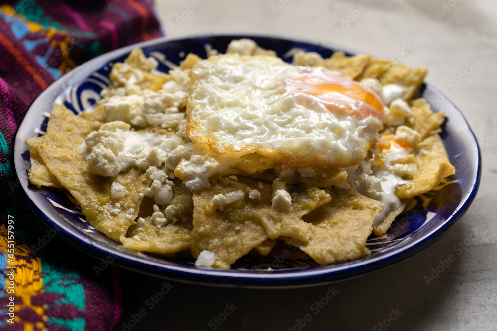 Mexican food. Green chilaquiles with cheese and fried egg on grey background Mexican food. Green chilaquiles with cheese and fried egg on grey background