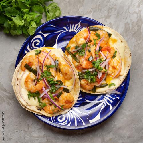 Mexican food. Shrimp tacos with melted cheese and poblano pepper called gobernador on grey background.