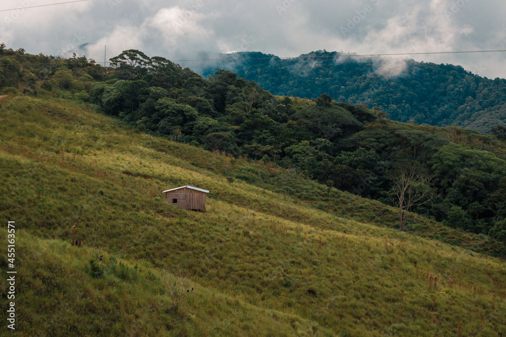 Horizontal shot of country house in the middle of a landscape with green mountains on a cloudy day Horizontal shot of country house in the middle of a landscape with green mountains on a cloudy day