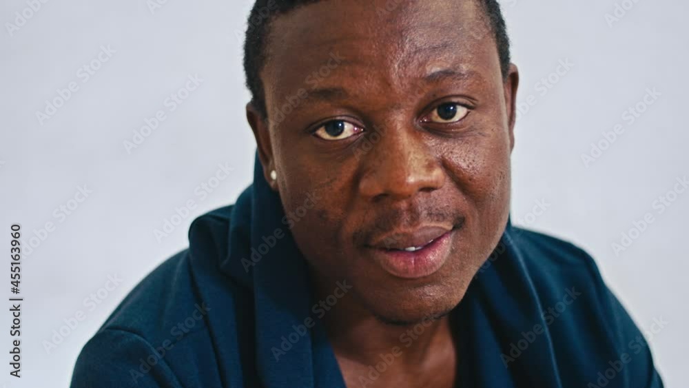 happy african guy sitting on bed smiling at camera, close-up happy african guy sitting on bed smiling at camera, close-up