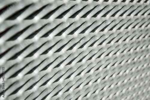 A close-up view of a metal grille on a window against thieves made of perforated drawn aluminum.