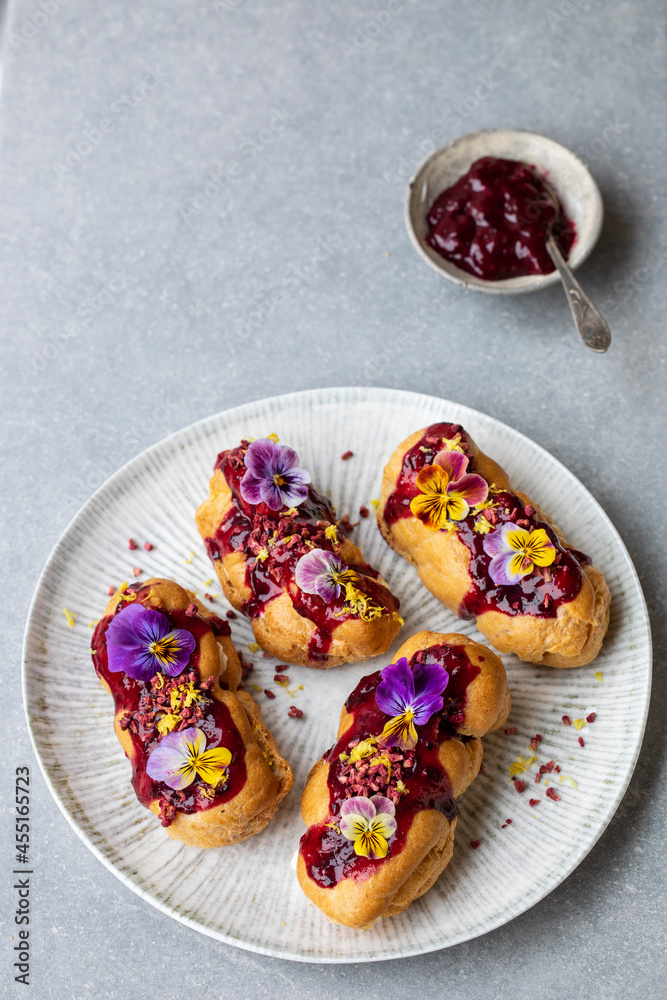 Small eclairs with bluberry icing and violet flowers Small eclairs with bluberry icing and violet flowers
