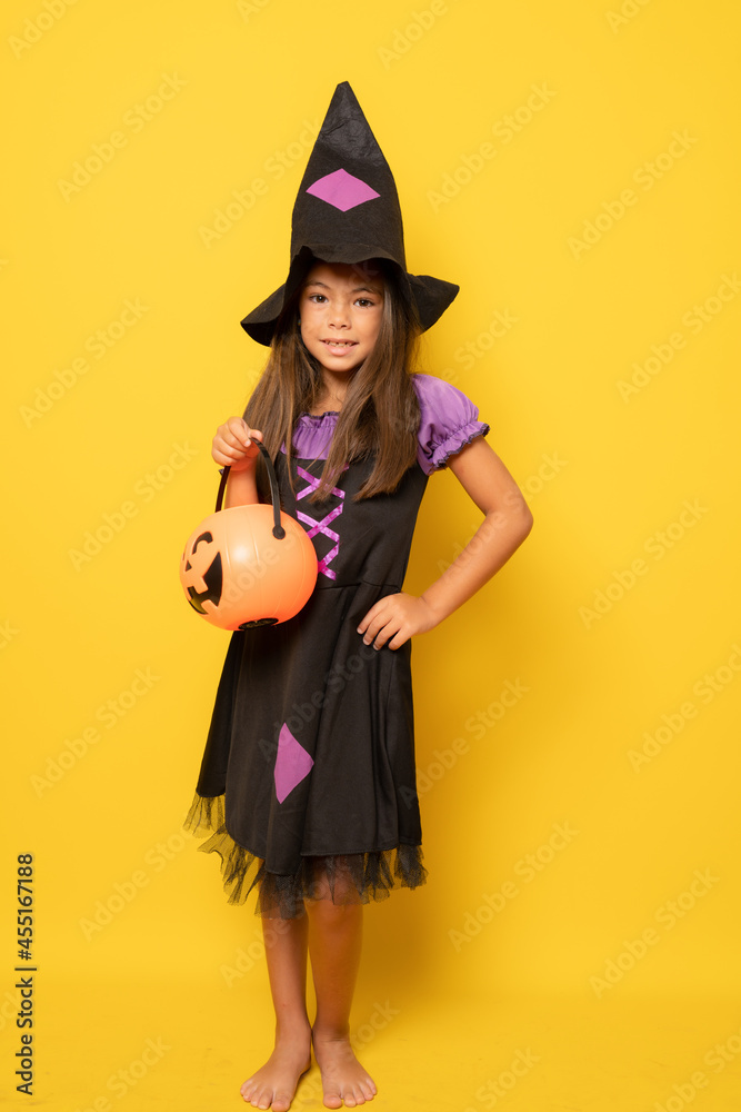 Beautiful little girl in Halloween costume isolated over yellow background.Halloween, carnival, childhood, fairytale theme.