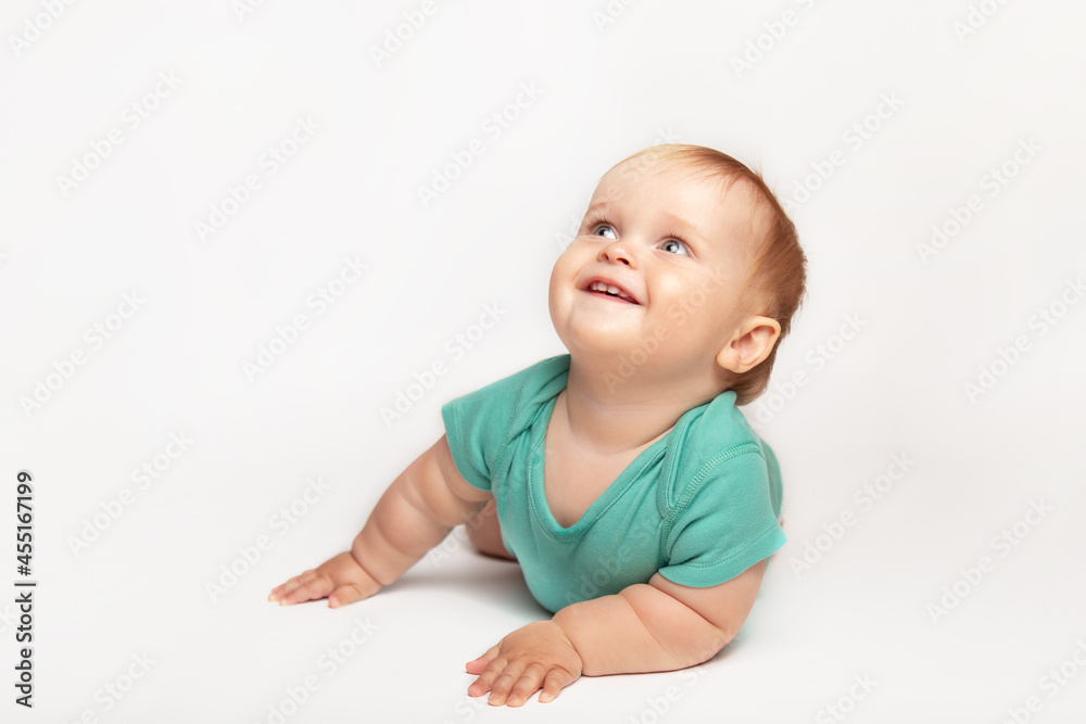 Cute small caucasian toddler baby boy child crawl on white studio floor. Smiling little infant kid wearing a green t-shirt explore world. Childcare and upbringing concept. Cute small caucasian toddler baby boy child crawl on white studio floor. Smiling little infant kid wearing a green t-shirt explore world. Childcare and upbringing concept.