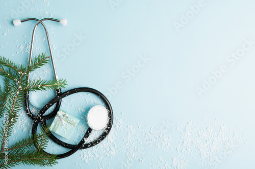 Christmas medical concept with stethoscope, gift box and christmas tree on blue