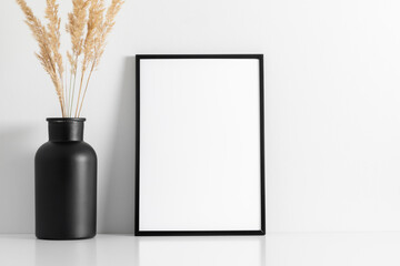 Black photo frame mockup on wall with reeds decoration 