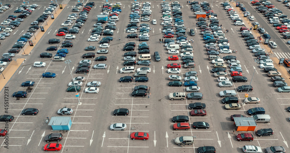 Fototapeta premium Shopping mall parking lot with many cars, aerial top view from drone.